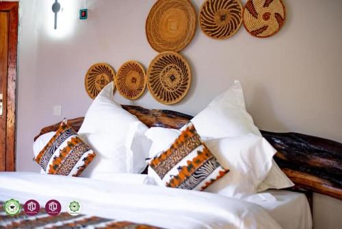een slaapkamer met een bed met kussens en hoeden aan de muur bij Twalumba Resort & Village in Mwanachunga