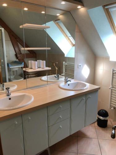 une salle de bain avec deux lavabos et un grand miroir dans l'établissement Les pouges, à Chameyrat