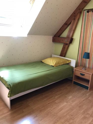 - une chambre mansardée avec un lit vert dans l'établissement Les pouges, à Chameyrat