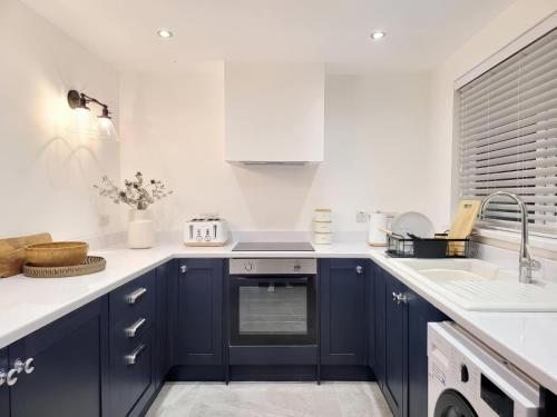 a kitchen with blue cabinets and a sink at Sandy Beaches Portrush - Steps from Beach & Dining in Portrush