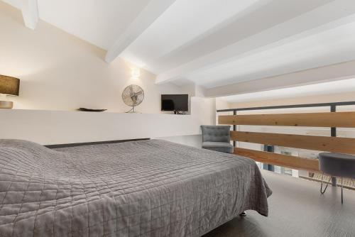 une chambre avec un lit, une télévision et une chaise dans l'établissement Naturistecapdagde village naturiste Nude, au Cap d'Agde