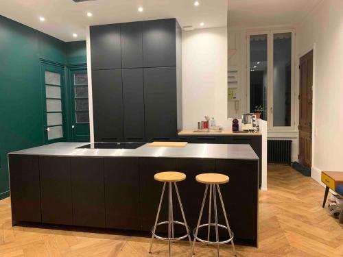 une cuisine avec un îlot noir et des tabourets de bar dans l'établissement Ainay - Luxury apartment - 2 bedroom and 2 bathroom, à Lyon