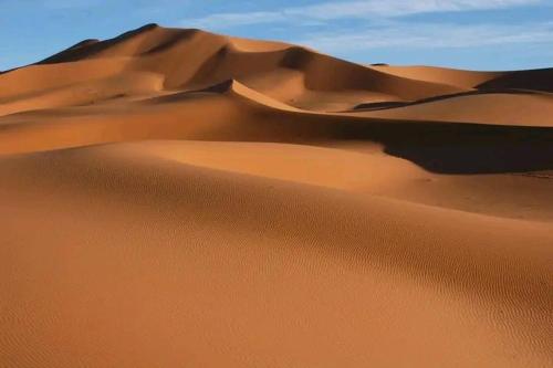 a sand dune in the desert with the sky in the background at Desert Erg Chigaga Camp in El Gouera