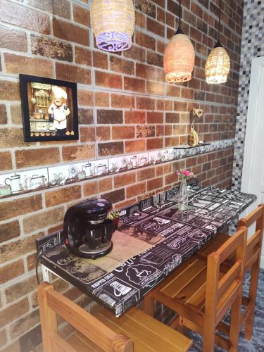 a brick wall with a table with a tea kettle on it at Hostel da Rô, Praia Grande in Praia Grande