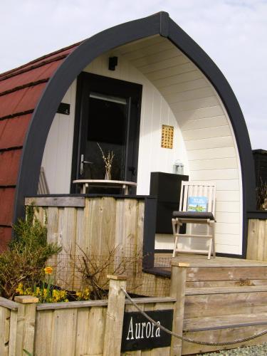 an arched doorway to a house with a chair on the porch at Harlosh Hideaways - Aurora Pod in Harlosh