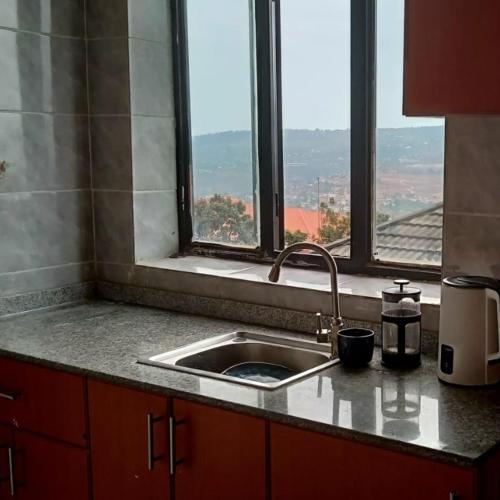 Una encimera de cocina con un fregadero y una ventana. en Xenia house, en Kigali