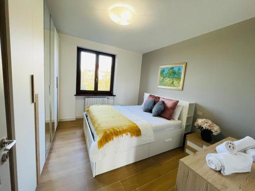 a bedroom with a large white bed and a window at Holiday Flat in Villa San Gregorio with pool in Melazzo