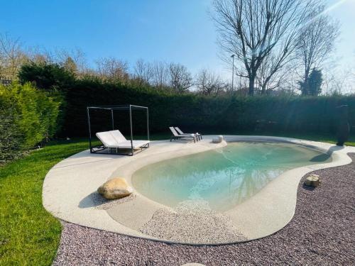 a small pool with two chairs and a bench at Holiday Flat in Villa San Gregorio with pool in Melazzo