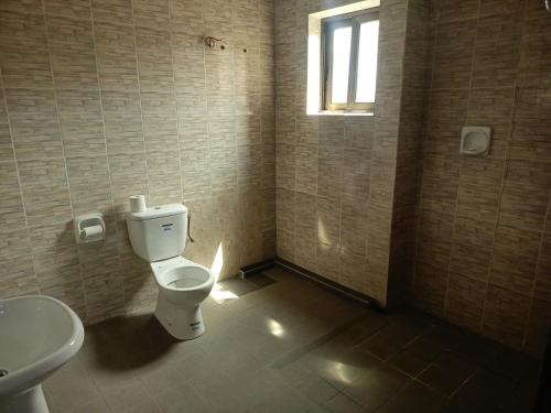 a bathroom with a toilet and a sink and a window at HOTEL GEORGES 5 Bénin in Cotonou