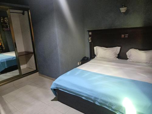 a bedroom with a large bed and a large mirror at HOTEL GEORGES 5 Bénin in Cotonou