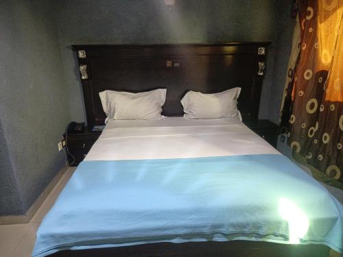 a bedroom with a large bed with a wooden headboard at HOTEL GEORGES 5 Bénin in Cotonou