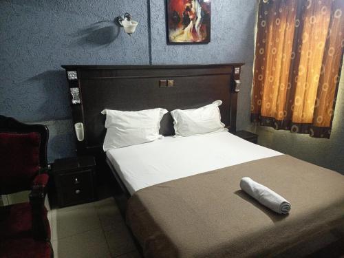 a bedroom with a bed with a pillow on it at HOTEL GEORGES 5 Bénin in Cotonou