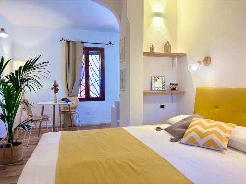 a bedroom with a bed with a yellow headboard and a table at Residence La Rosa in Porto San Paolo