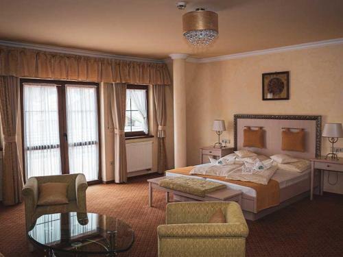 a bedroom with a bed and a chair and a table at Hétkúti Wellness Hotel in Mór