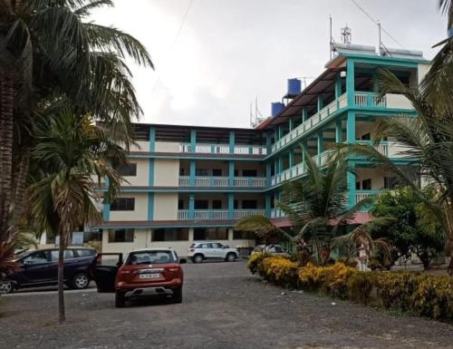 a large building with cars parked in front of it at Atithi farmhouse in Alibaug