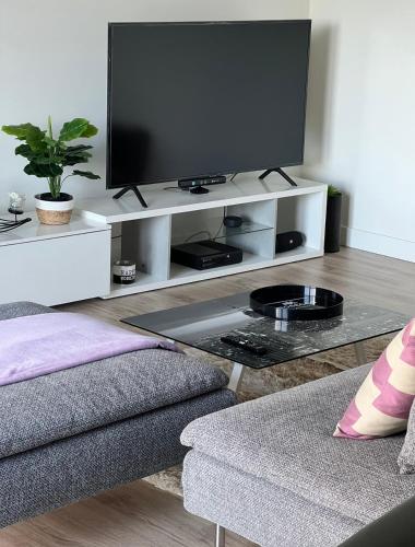 a living room with a television on a white entertainment center at Modern Big Room with Balcony in New Apartment in Montijo