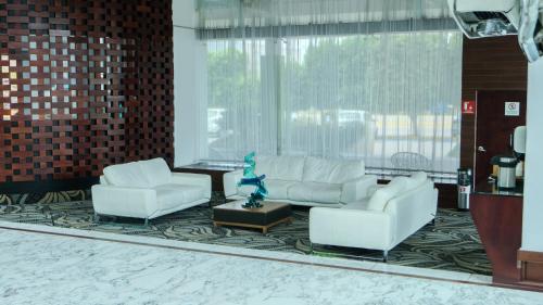 a living room with white furniture and a large window at Holiday Inn Queretaro Zona Krystal by IHG in Querétaro