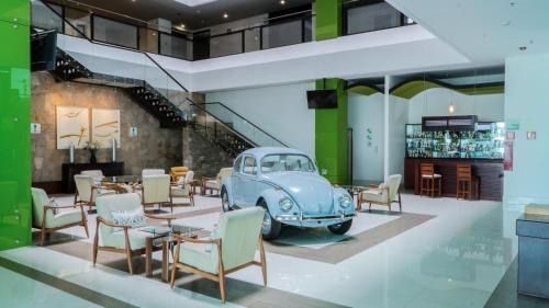 a room with an old car and tables and chairs at Holiday Inn Queretaro Zona Krystal by IHG in Querétaro
