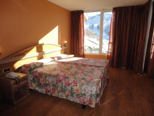 una habitación de hotel con una cama y una ventana grande en Hotel Reino Nevado, en Sierra Nevada