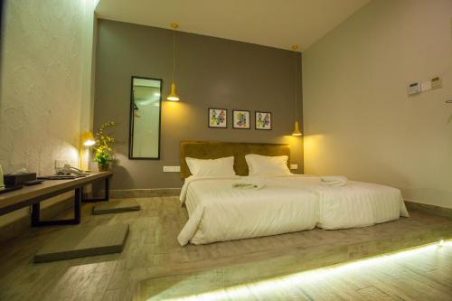 a bedroom with a large white bed and a desk at Bzz Hotel Skudai in Skudai