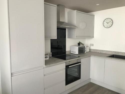 a kitchen with white cabinets and a clock on the wall at On The Avenue Apt 4 in Nottingham