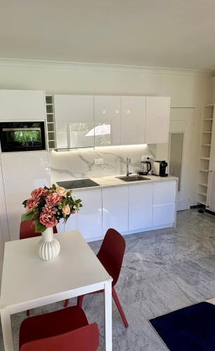 une cuisine avec des placards blancs et un vase de fleurs sur une table dans l'établissement T2 close to the beach, à Antibes