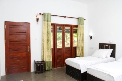 a bedroom with two twin beds and a door at Yala Way Hide Resort in Tissamaharama