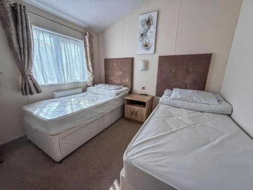 a bedroom with two beds and a window at Luxury 6 Berth Lodge With Wifi At Broadland Sands In Suffolk Ref 20011Cv in Hopton on Sea