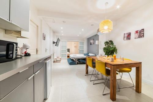 une cuisine et une salle à manger avec une table en bois et des chaises jaunes dans l'établissement Loft moderne face jardin des plantes - 4P, à Paris