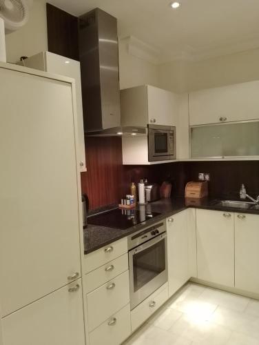 a kitchen with white cabinets and stainless steel appliances at Beautiful apartment in Kew, Richmond London with Free Underground Parking in London