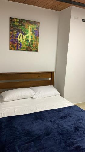 a bed in a bedroom with a painting on the wall at Finca turística el paraíso es aqui in Vergara
