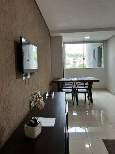 a living room with a table and a tv on the wall at Apartamento 102 in João Monlevade