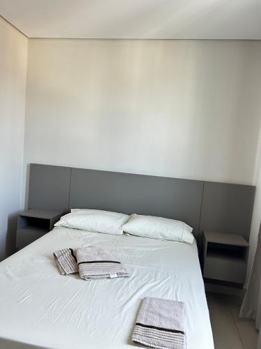 a white bed with two towels on top of it at Apartamento 102 in João Monlevade