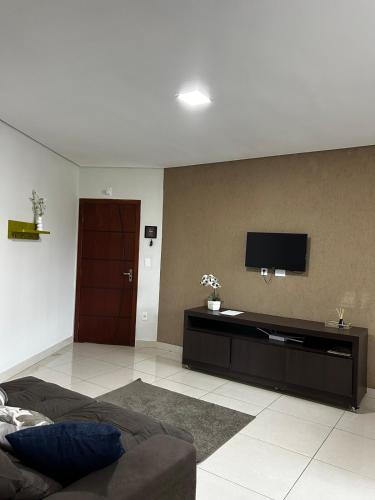 a living room with a couch and a tv on the wall at Apartamento 102 in João Monlevade