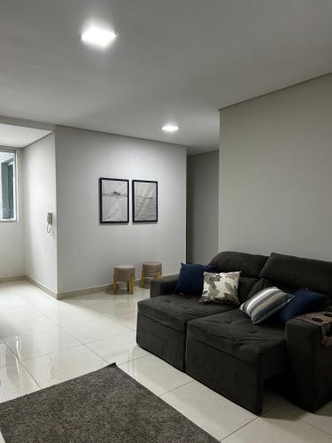 a living room with a black couch and a white wall at Apartamento 102 in João Monlevade