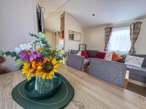 a vase of flowers on a table in a living room at Stunning10 Berth Caravan With Decking At Broadland Sands In Suffolk Ref 20082Bs in Hopton on Sea