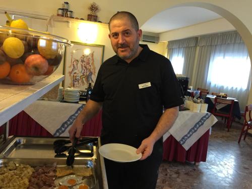 a man holding a white plate in front of a buffet at Hotel Riviera in Alghero