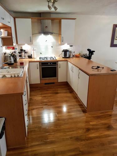 a kitchen with white cabinets and a wooden floor at 1 Bedroom luxury Flat Close to town center in Northampton