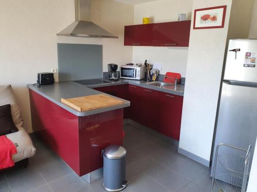 Elle comprend une petite cuisine équipée de placards rouges et d'un réfrigérateur. dans l'établissement Mer et pins, à Saint-Philibert