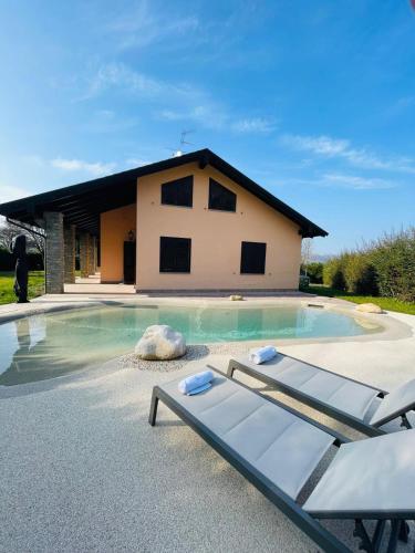 a swimming pool with two lounge chairs in front of a house at Holiday Flat in Villa San Gregorio with pool in Melazzo