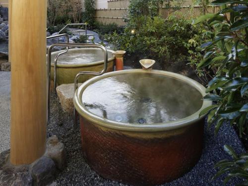 a large bath tub sitting next to a bush at Kobe Minato Onsen Ren in Kobe