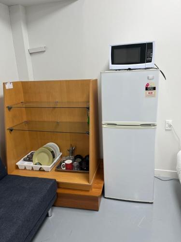 a kitchen with a refrigerator and a microwave on top of it at 2 Double Beds, 1 Single Bed, 2 Double Sofa Beds in 1 Room, Serviced Suite 6 in Auckland