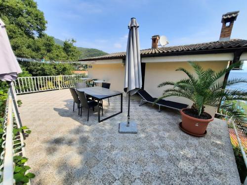 a patio with an umbrella and a table and chairs at Rooms Vid&Rok in Mošćenička Draga
