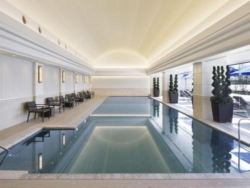 a swimming pool in a building with tables and chairs at Kobe Minato Onsen Ren in Kobe