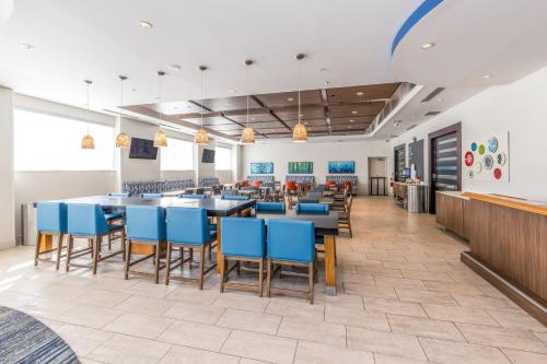 a dining area with blue chairs and tables in a cafeteria at Holiday Inn Express & Suites Downtown Louisville by IHG in Louisville
