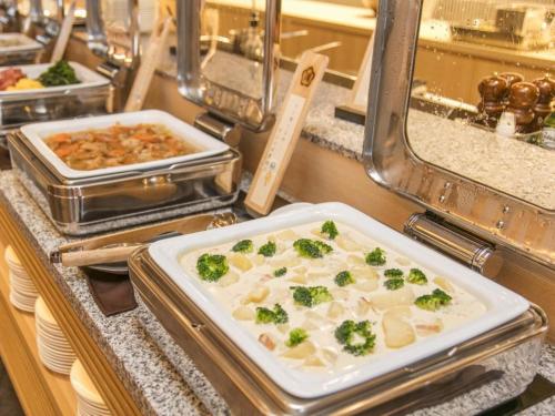a buffet line with a plate of food with broccoli at Kobe Minato Onsen Ren in Kobe