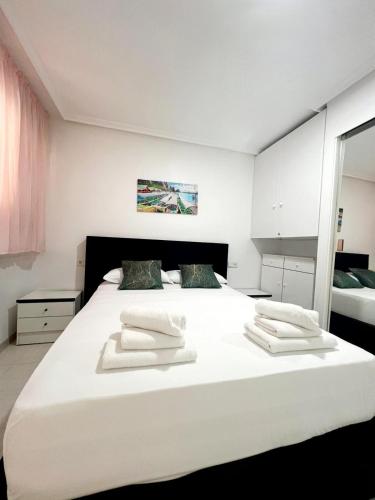 a bedroom with a large white bed with two white towels at Holiday Apartment in Torrevieja