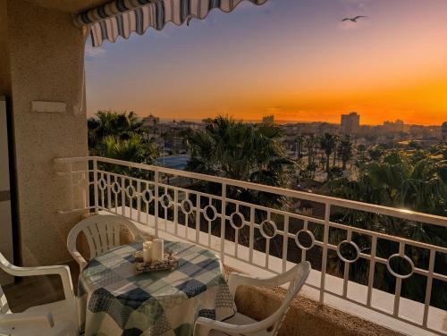 a balcony with a table and chairs and a sunset at Vive Santa Pola - Relax y tranquilidad junto al mar in Santa Pola