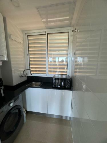 a small kitchen with a sink and a washing machine at Casa Felicita Playa Azul in El Borseral