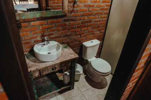 La salle de bains est pourvue de toilettes, d'un lavabo et d'un mur en briques. dans l'établissement Chalé Sanga, à Jaraguá do Sul